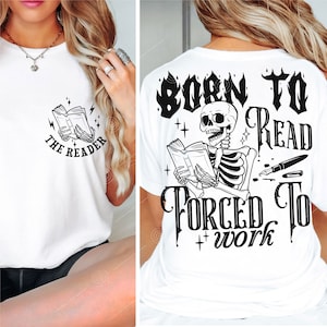 May include: White t-shirt with a black and white graphic of a skeleton reading a book. The text on the shirt says "Born to Read Forced to Work".