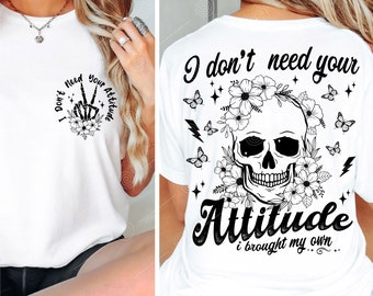 May include: White t-shirt with a black skull and floral design. The text on the shirt reads "I don't need your attitude I brought my own..."