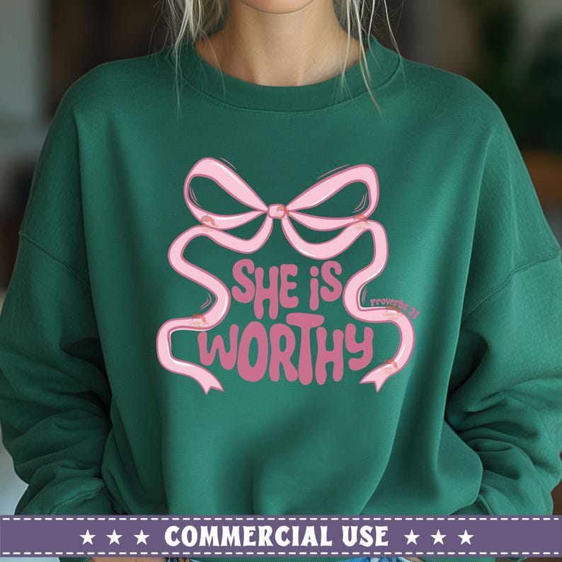 May include: A green sweatshirt with a pink bow and the text "She is worthy" in a pink, cursive font. The text "Proverbs 31" is in a smaller font below the bow.