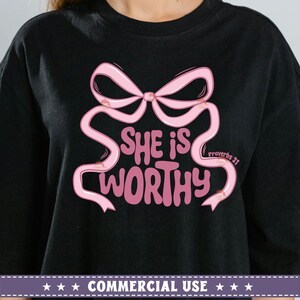 May include: Black t-shirt with a pink bow and the text "She is worthy" with "Proverbs 31" in smaller text below the bow.