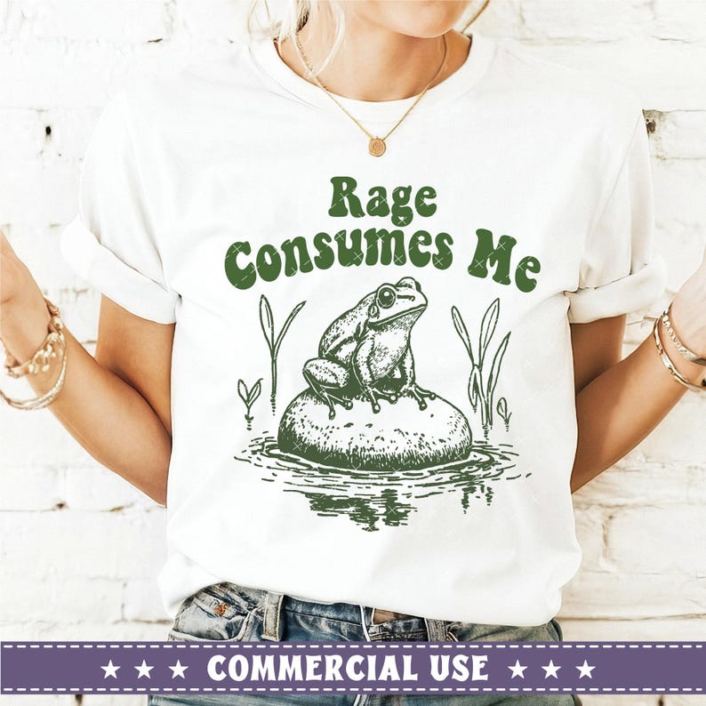 May include: White t-shirt with green text that reads "Rage Consumes Me" and a green illustration of a frog sitting on a rock in a pond.