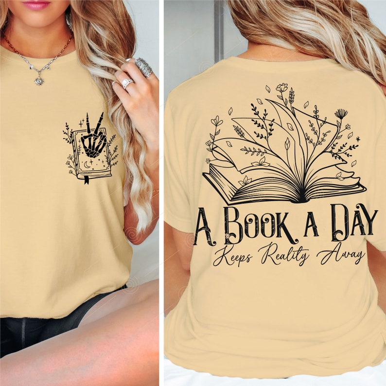 Op de afbeelding: Een beige T-shirt met een zwarte afbeelding van een open boek met bloemen die eruit groeien. De tekst "A Book A Day Keeps Reality Away" is onder het boek gedrukt.