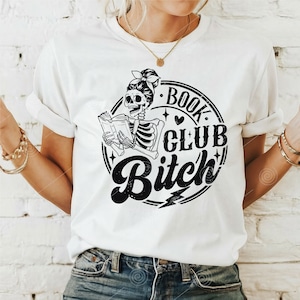 May include: White t-shirt with a black and white graphic of a skeleton reading a book. The graphic is inside a circle with the text "Book Club Bitch" in a distressed font.