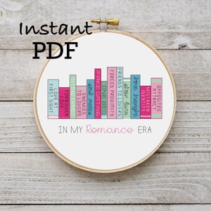 May include: A cross-stitch embroidery hoop featuring a design of colorful book spines. The text "Instant PDF" is at the top, and "IN MY Romance ERA" is at the bottom. The book titles include "Love at First Sight" and "Opposites Attract".