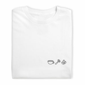 Könnte beinhalten: Weißes T-Shirt mit einer einfachen Linienzeichnung einer Kaffeetasse, einem Kaffeerührer und zwei Kaffeebohnen.