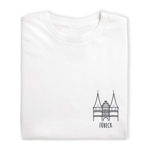 Könnte beinhalten: Weißes T-Shirt mit einer schwarzen Linienzeichnung des Holstentores in Lübeck, Deutschland. Der Text "LÜBECK" ist unter der Zeichnung gedruckt.