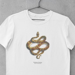 Pode incluir: Camiseta branca com um gráfico de uma pitão birmanesa, um tipo de cobra, em posição enrolada. O texto "Burmese Python" e "Python Bivittatus" está impresso abaixo da cobra.