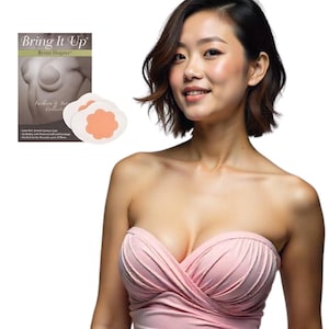 Puede incluir: Una mujer con un top rosa sin tirantes. La imagen también muestra una caja de "Bring It Up" Breast Shapers y dos cubiertas para pezones en forma de pétalo naranja y blanco.
