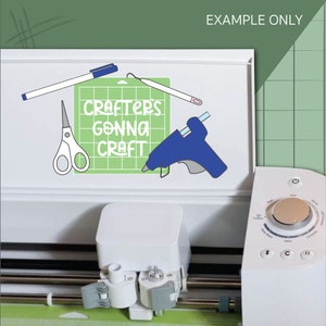 Op de afbeelding: Een witte knutselmachine met een groene snijmat en een blauwe lijmpistool. De snijmat heeft de tekst "Crafter's Gonna Craft" erop.