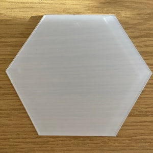 Può includere: Un sottobicchiere esagonale bianco in vetro.