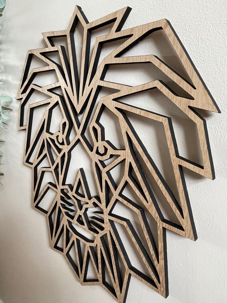 May include: Geometric wooden lion head wall art with a black outline. The lion's mane is made up of many triangles and the face is detailed with eyes, nose, and mouth.