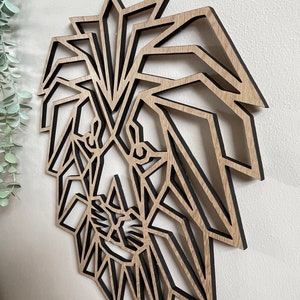 May include: Geometric wooden lion head wall decor with a black outline. The lion's face is made up of triangles and other geometric shapes.