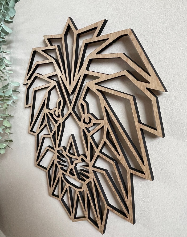 May include: Geometric wooden lion head wall decor with a black outline. The lion's face is made up of triangles and other geometric shapes.