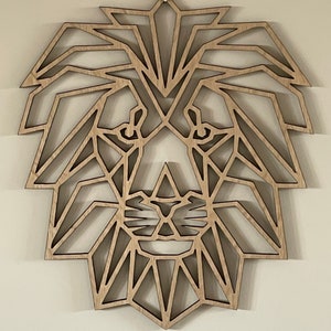 May include: Geometric wooden lion head wall decor. The lion's mane is made up of intricate triangles and the face is detailed with a nose and eyes.
