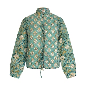 Puede incluir: Chaqueta acolchada turquesa con un estampado floral en blanco y amarillo. La chaqueta tiene cuello alto, mangas largas y cierre de lazo. El patrón floral se repite en todo el diseño de la chaqueta.