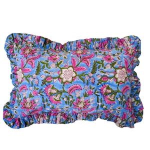 Puede incluir: Una almohada azul con un estampado floral rosa y verde y un borde con volantes.