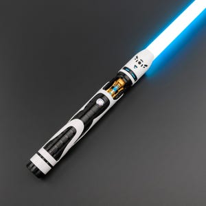 May include: A futuristic lightsaber with a bright blue blade. The hilt features a black and white design with intricate details, including a circular button and exposed internal components. The overall aesthetic is sleek and modern.