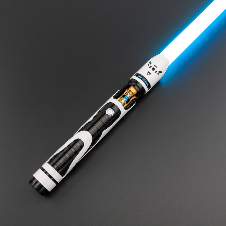May include: A futuristic lightsaber with a bright blue blade. The hilt features a black and white design with intricate details, including a circular button and exposed internal components. The overall aesthetic is sleek and modern.