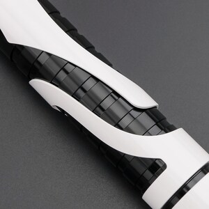 May include: A close-up of a futuristic-looking black and white object. The object has a cylindrical shape with a series of black rings and white, curved accents. The design is sleek and modern, with a focus on geometric shapes and contrasting colors.