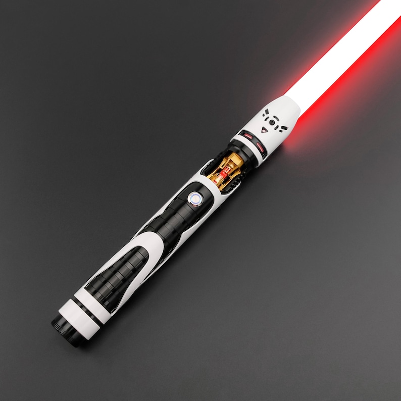May include: A white and black lightsaber with a red blade. The hilt features a detailed design with a circular button and exposed internal components. The blade emits a bright red glow, suggesting an active state. The overall design is futuristic and sleek.