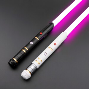 May include: Two lightsabers with glowing purple blades. One is black with gold accents and a red button, the other is white with gold and silver accents and a red button. The hilts have intricate designs.