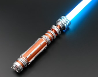 May include: A lightsaber with a metallic orange and silver hilt and a bright blue blade. The hilt has intricate details and a cylindrical design. The blade emits a bright, glowing light, suggesting a futuristic or science fiction theme.