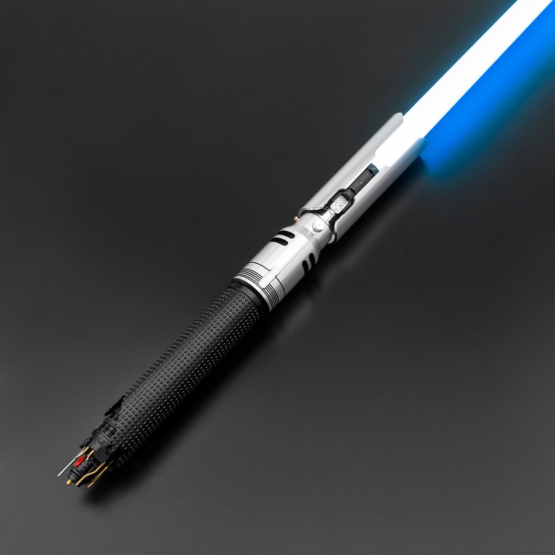 K&ouml;nnte beinhalten: Ein silbernes und schwarzes Lichtschwert mit einer blauen Klinge. Das Lichtschwert hat einen strukturierten schwarzen Griff und einen silbernen Griff mit einem Knopf.