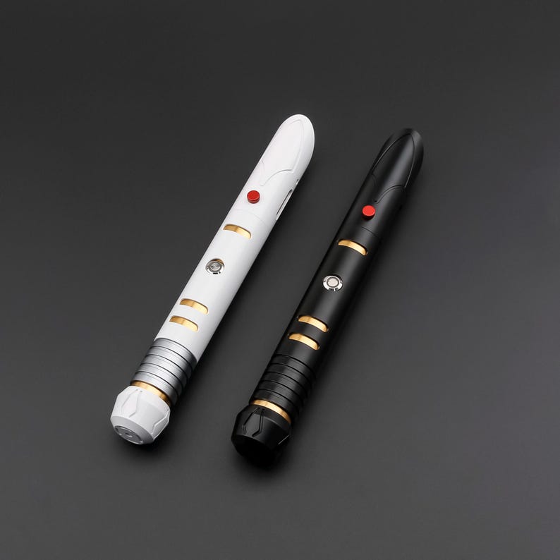 May include: Two lightsabers, one white and one black, are displayed against a dark background. The white lightsaber has gold and silver accents, with a red button. The black lightsaber has gold accents and a red button. Both have a futuristic design.