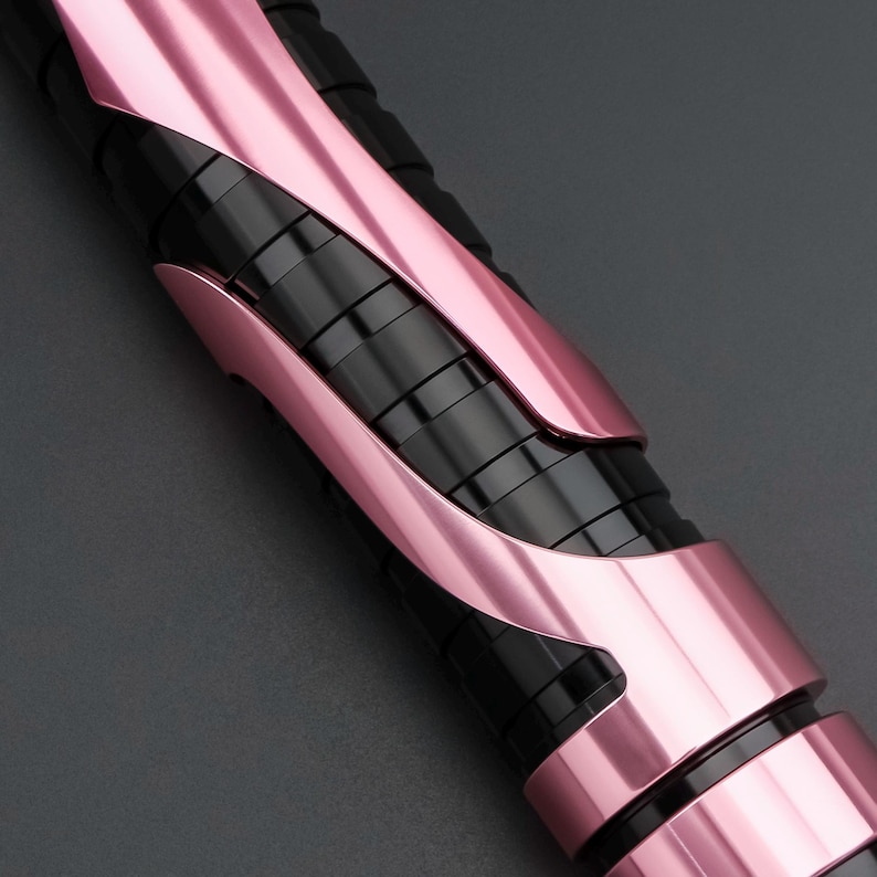 May include: Close-up of a black and pink object with a sleek, modern design. The object features a series of black, cylindrical segments encased in curved, metallic pink panels. The color scheme creates a striking contrast, highlighting the object's form.