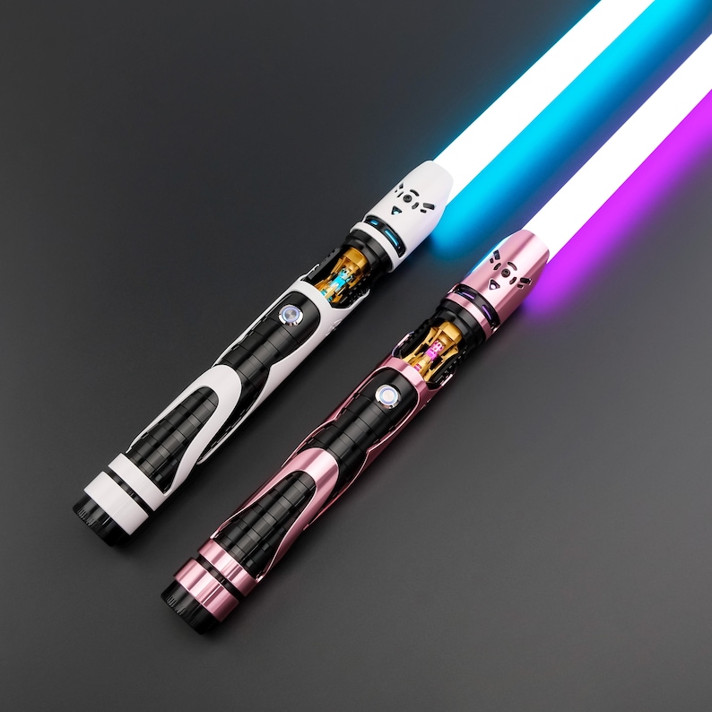 May include: Two illuminated lightsabers. One is white and black with a blue blade, the other is pink and black with a purple blade. Both have intricate metallic detailing and a futuristic design, set against a dark background.