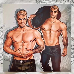May include: Art print depicting two muscular men with tattoos. One wears olive green trousers, the other black. Both are shirtless with blonde hair and serious expressions. The artwork is signed by the artist, Veradia.