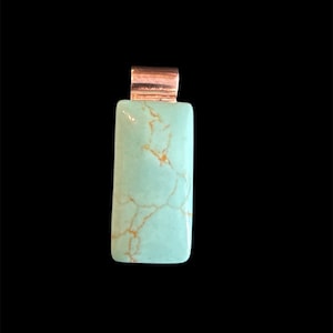 May include: A rectangular pendant with a light turquoise stone and copper-colored metal accents. The stone has a unique pattern of brown veins. The pendant is set against a black background.