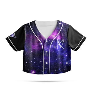 May include: A black and white baseball jersey with a galaxy print. The jersey has a white collar and white trim around the sleeves. The jersey has a white button placket and a white 'K' on the front. The jersey has a small planet graphic on the left sleeve.
