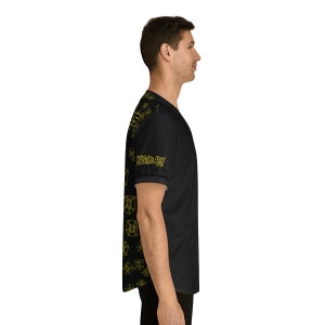 May include: Black baseball jersey with a yellow geometric pattern and the text "Cycles Are Fun" on the sleeve.