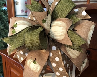 May include: A white lantern with a brown and white polka dot ribbon, a brown ribbon with white pumpkins, and a green ribbon with white pumpkins tied around it.
