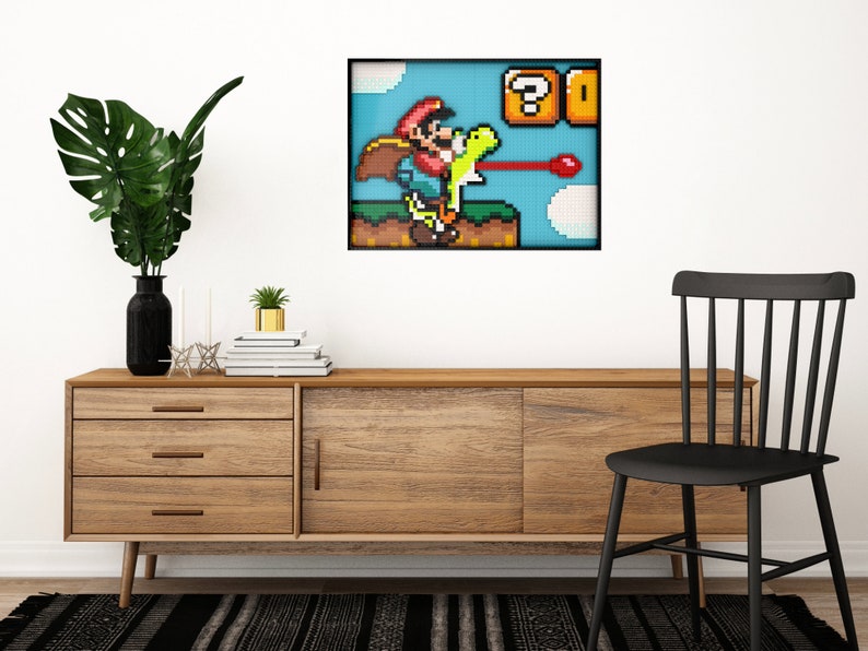May include: A framed pixel art print of a video game character, Mario, riding a dinosaur-like creature and firing a red projectile. The background is a blue sky with clouds and a question mark block with a coin inside.