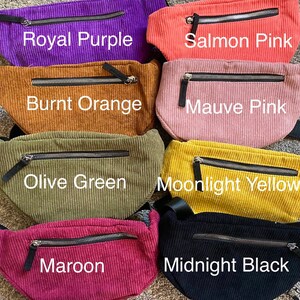 May include: Seven different colored corduroy fanny packs with zipper closures. The colors are royal purple, salmon pink, burnt orange, mauve pink, olive green, moonlight yellow, and midnight black.