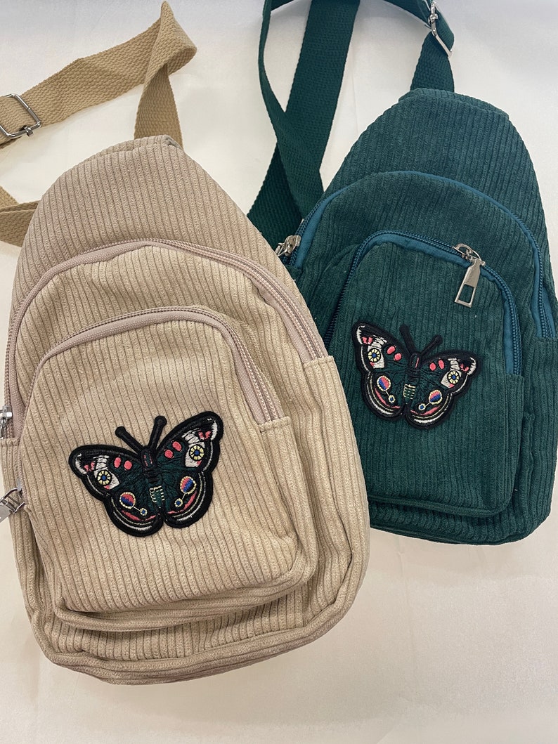 May include: Two corduroy crossbody bags with butterfly patches. One bag is beige and the other is green.