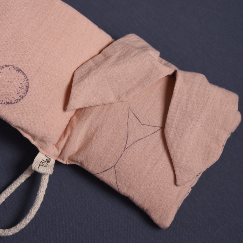 May include: A light pink fabric pouch with a star and circle design. The pouch has a drawstring closure and a small label that says "YOLK".