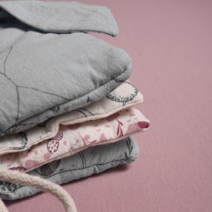 May include: A stack of four fabric squares with different floral patterns. The top square is a light blue color with a simple design, the second square is a cream color with a floral pattern, the third square is a light pink color with a floral pattern, and the bottom square is a light blue color with a simple design.