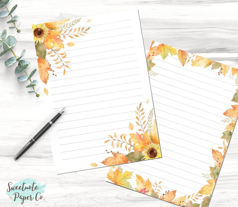 May include: Two sheets of lined stationery paper with a fall theme. The paper has a border of watercolor sunflowers, leaves, and branches in shades of yellow, orange, and brown. The text "Sweetnote Paper Co." is in the bottom left corner.