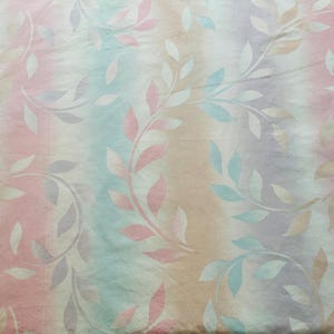 May include: A white fabric with a pastel pink, blue, and beige striped pattern. The fabric has a repeating leaf design.