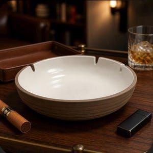 May include: A round ceramic ashtray with a smooth white interior and a textured, ribbed brown exterior. The ashtray features two notches on the rim for resting items. The design is simple and functional, showcasing a contrast between the light inner basin and the darker, earthy outer wall of the vessel.
