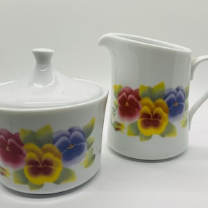 May include: A white ceramic mug with a black handle and the text "But First, Coffee" in a black, bold font. The mug is on a white surface.