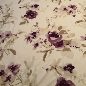 May include: Floral pattern featuring watercolor-style flowers in shades of purple, mauve, and beige against a cream background. The design includes various floral arrangements, with some blooms fully open and others in bud form. The overall aesthetic is soft and romantic.