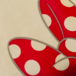May include: A red bow with white polka dots. The bow is made of a soft, plush fabric.