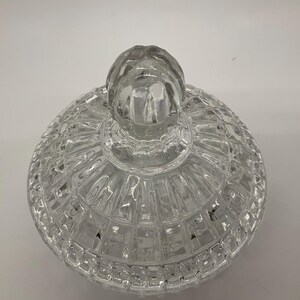 May include: A clear, glass candy dish lid with a textured, geometric pattern. The lid has a rounded shape with a knob on top for easy handling. The dish is designed to sit on a matching base, creating a decorative storage container.