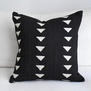 May include: Black and white throw pillow with a geometric pattern of white triangles on a black background.