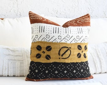 May include: A decorative throw pillow with a geometric pattern in shades of brown, white, and yellow. The pillow has a black and white geometric pattern on the bottom.