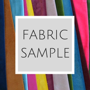 May include: A variety of fabric swatches in different colors, including blue, green, yellow, pink, and brown. The swatches are arranged in a row and have the text "FABRIC SAMPLE" written on a white rectangle in front of them.